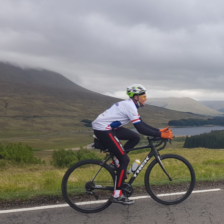 man cycling in Scotland with lake and mountains in the background