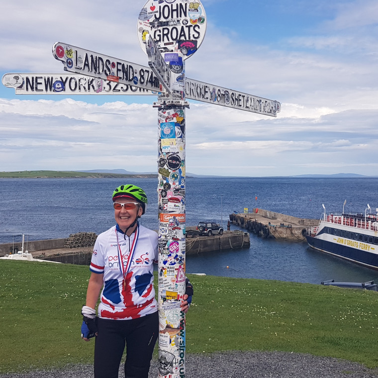 Picture of lady at JOG signpost with her medal