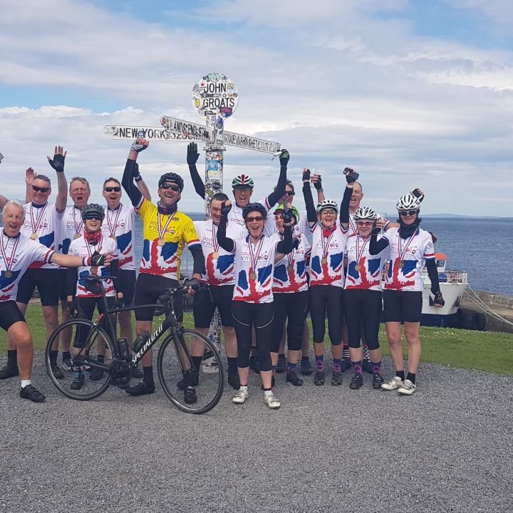 cyclists in front of John O'Groats sign